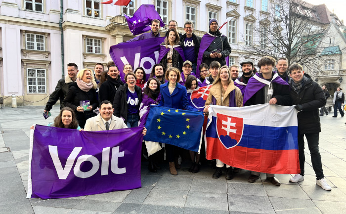 Členovia Volt Slovensko počas predvolebnej kampane v Bratislave. Členovia politickej strany Volt slovensko sa nachádzajú pred primaciálnym palácom v starom meste v Bratislave. Fotka vzniká počas letáčikovania v uliciach mesta. Politici držia vlajky strany Volt, slovenskú ale aj vlajku európskej únie, keďže sa jedná o jediné hnutie zasadzujúce sa o federalizáciu Európskej únie